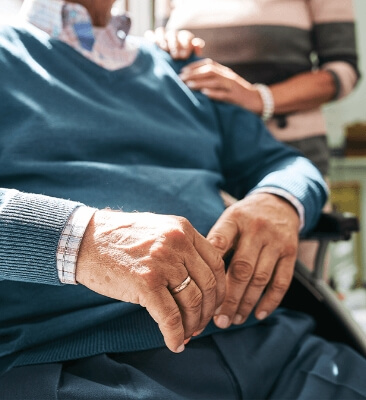 Senior man siting in a wheel chair and wife standing behind him